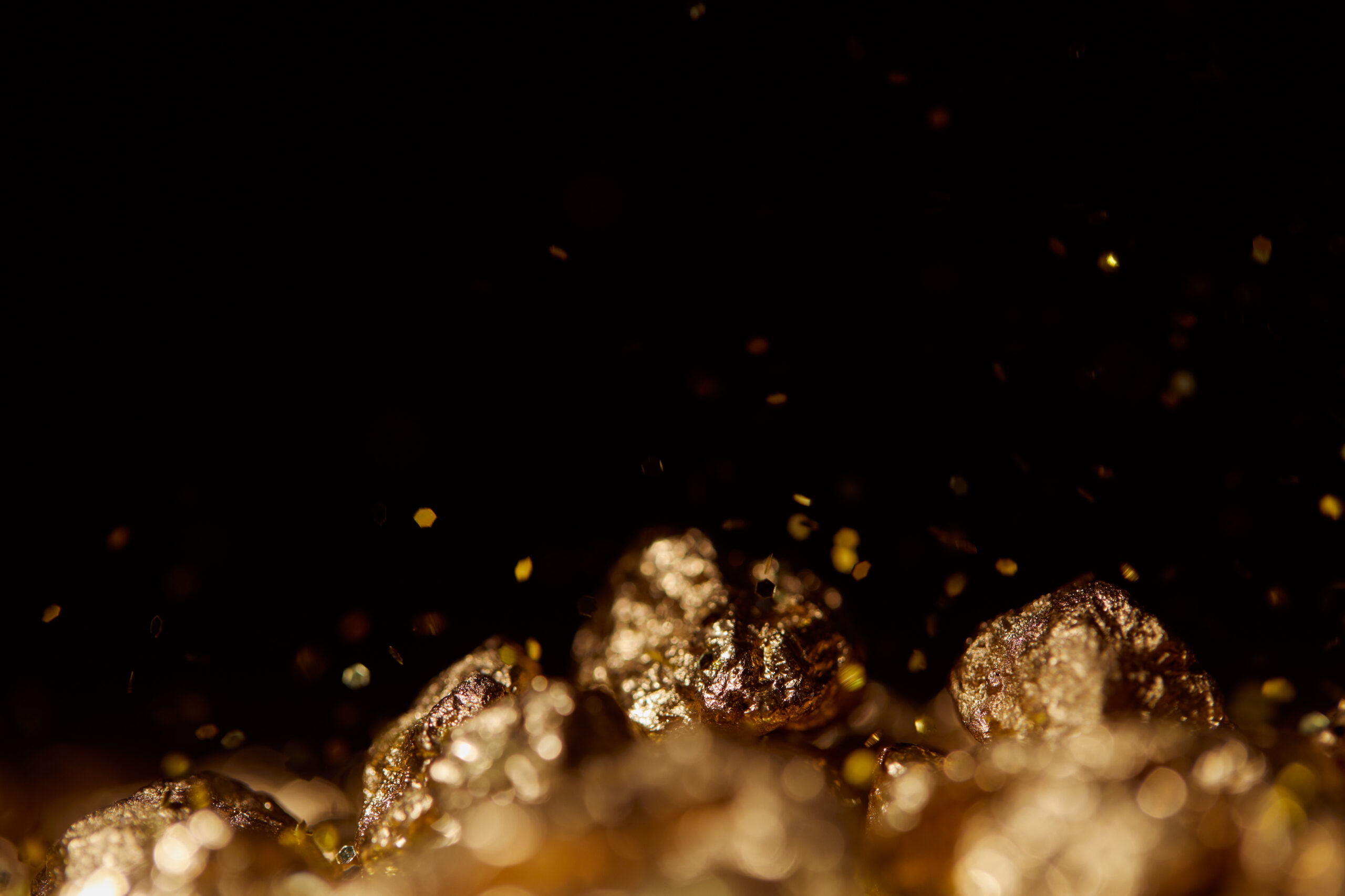 selective focus of golden stones with sparkling lights isolated on black